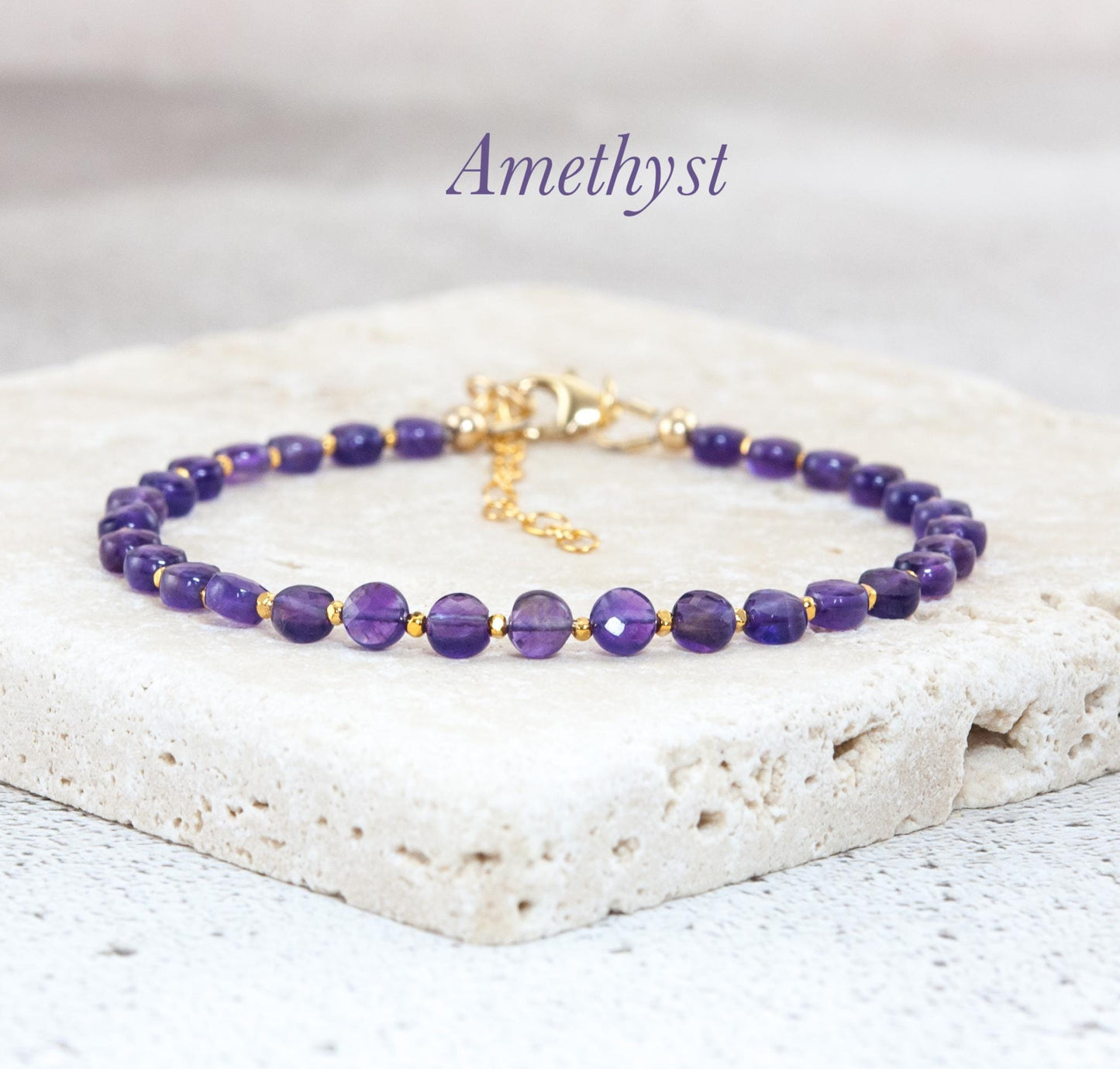 Amethyst bracelet with gold accents on a light stone surface, 'Amethyst' text above.